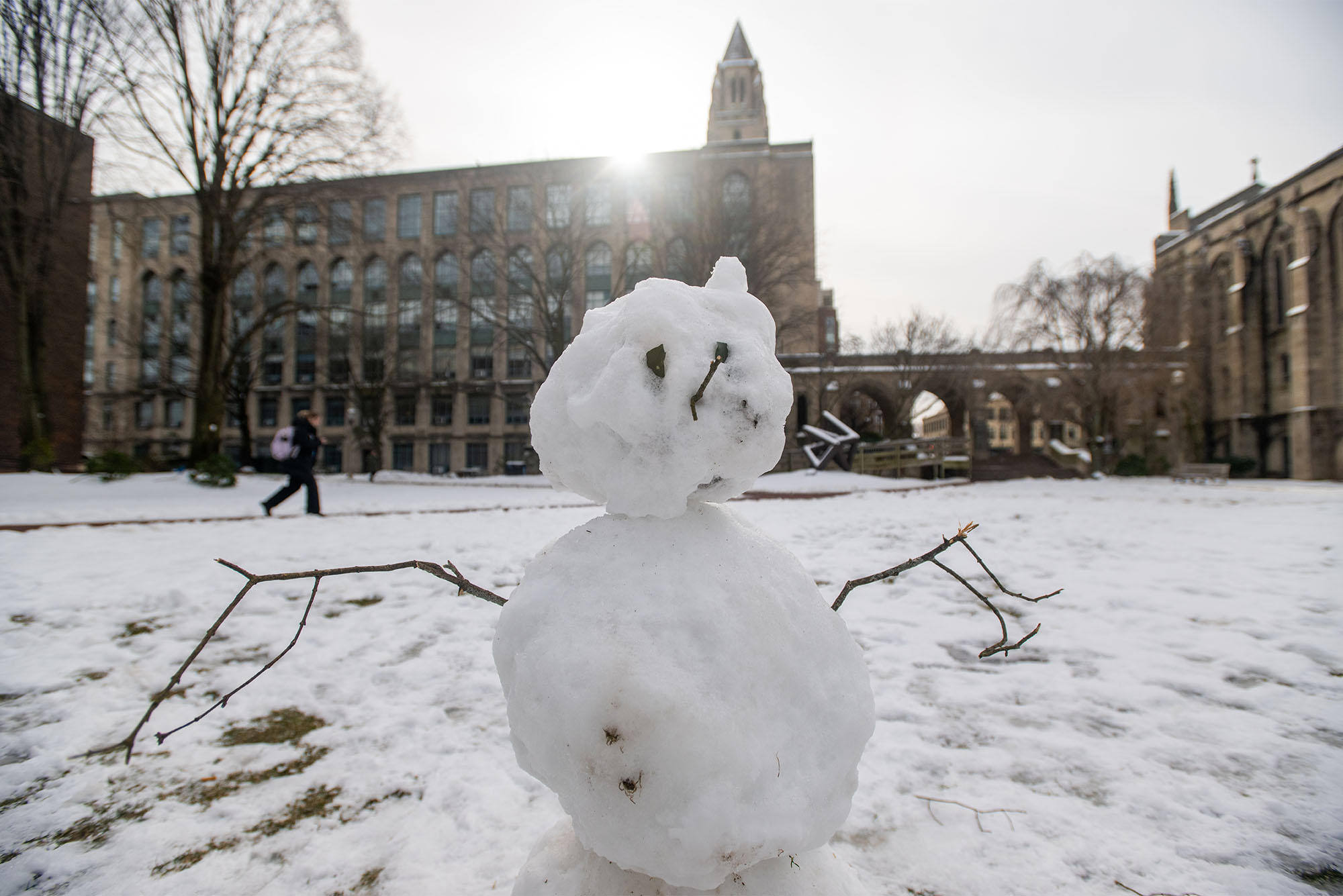 Photo: a snowman with stick arms and a hat on BU's campus on a cold winter day
