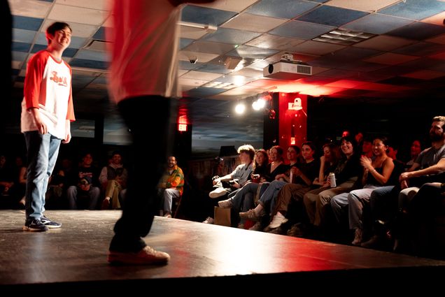 Photo: The main cast performs at Liquid Fun's monthly free imrpov show underneath the GSU at the BU Central venue. They wear baseball shirts and perform to a small audience on a small stage.