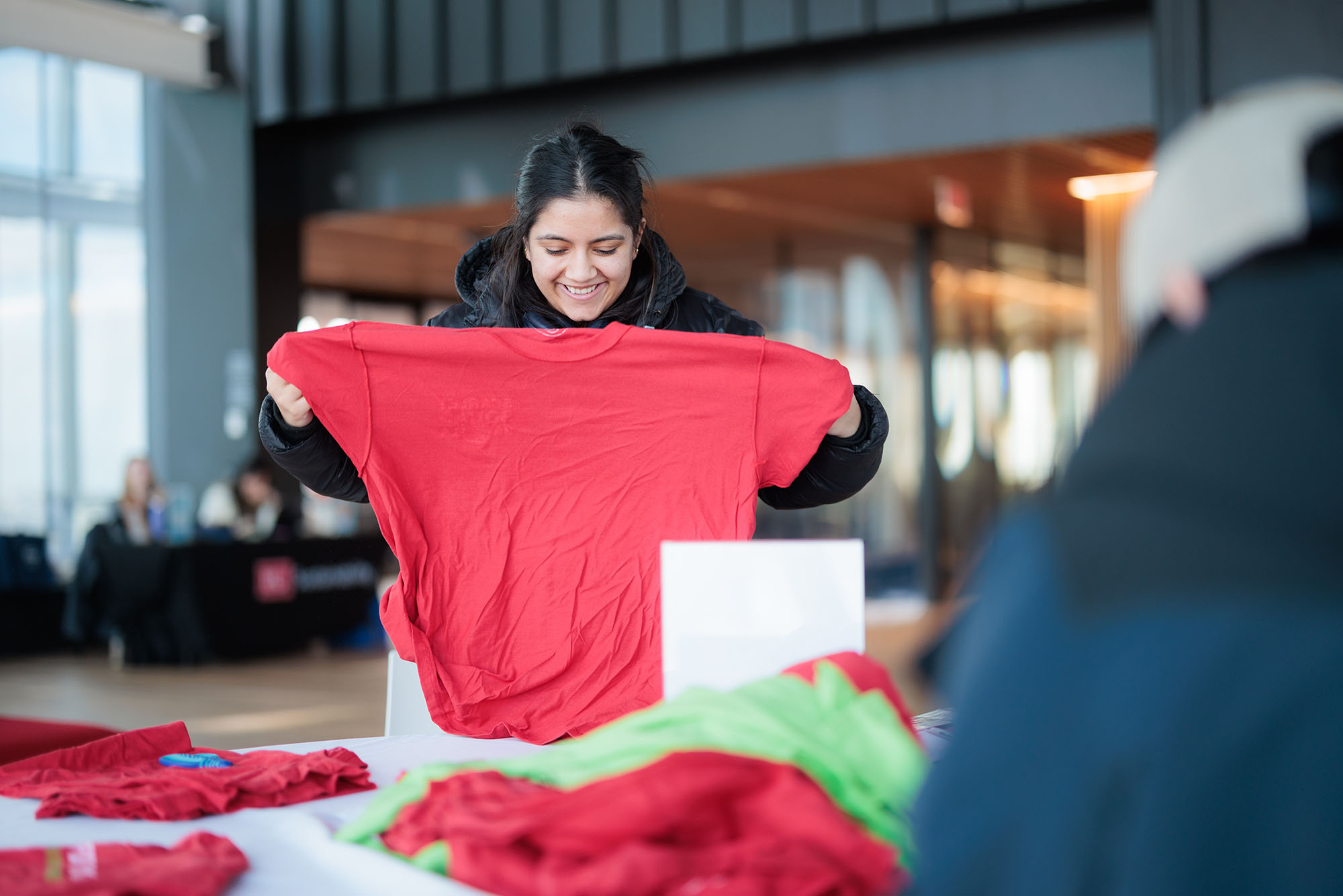 Photo: A young woman holds up a red tshirt at a event at BU.