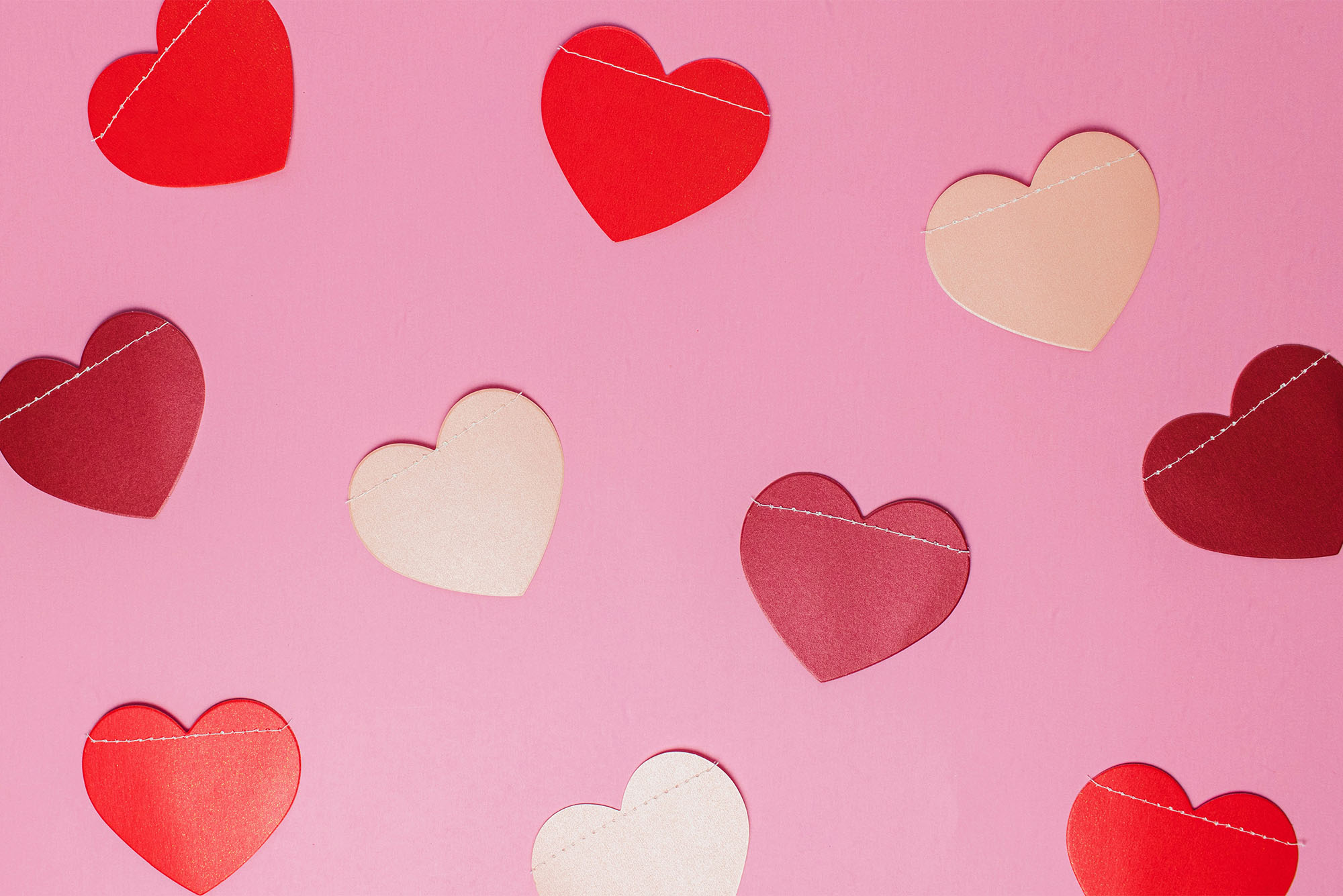 Photo: Paper cutouts of pink and red hearts on a pink paper background