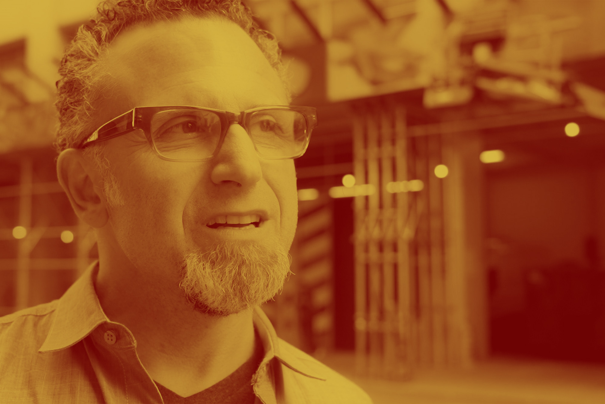 Photo: A man with glasses looking up with a yellow overlay on the picture