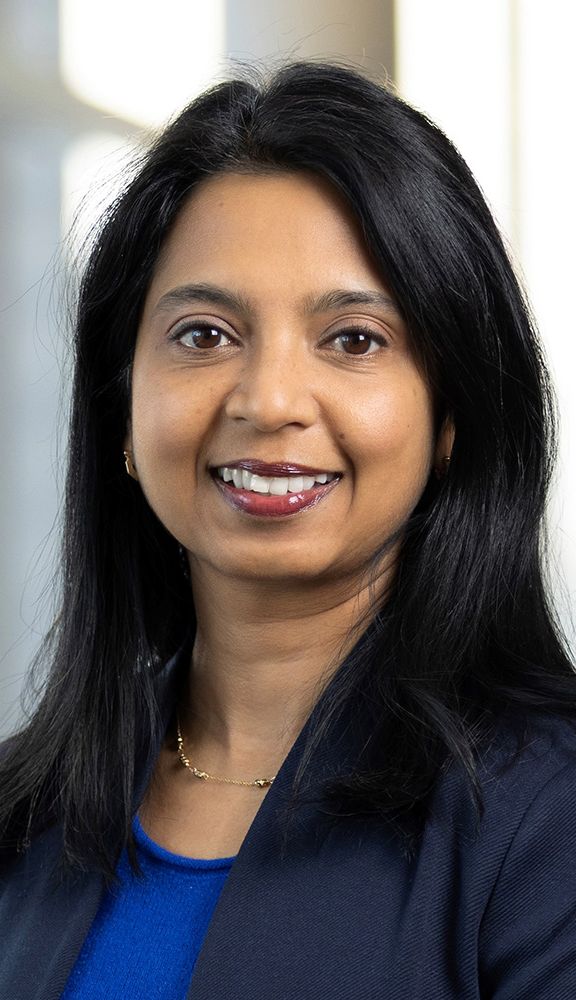 Photo: Portrait of Tuhina Neogi, a young South Asian woman with medium length dark hair and a bright smile.