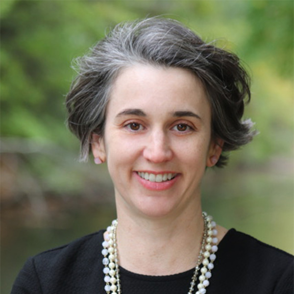 Photo: A woman wearing a pearl necklace with dark hair and a smile in this headshot portrait