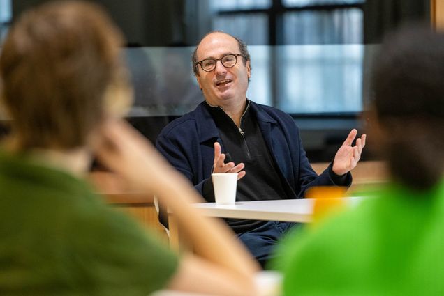 Photo: David Grann, a white man with balding hair, gestures as he speaks to a crowd of BU students for BU's discussion at Kilachand Hall Commons Room