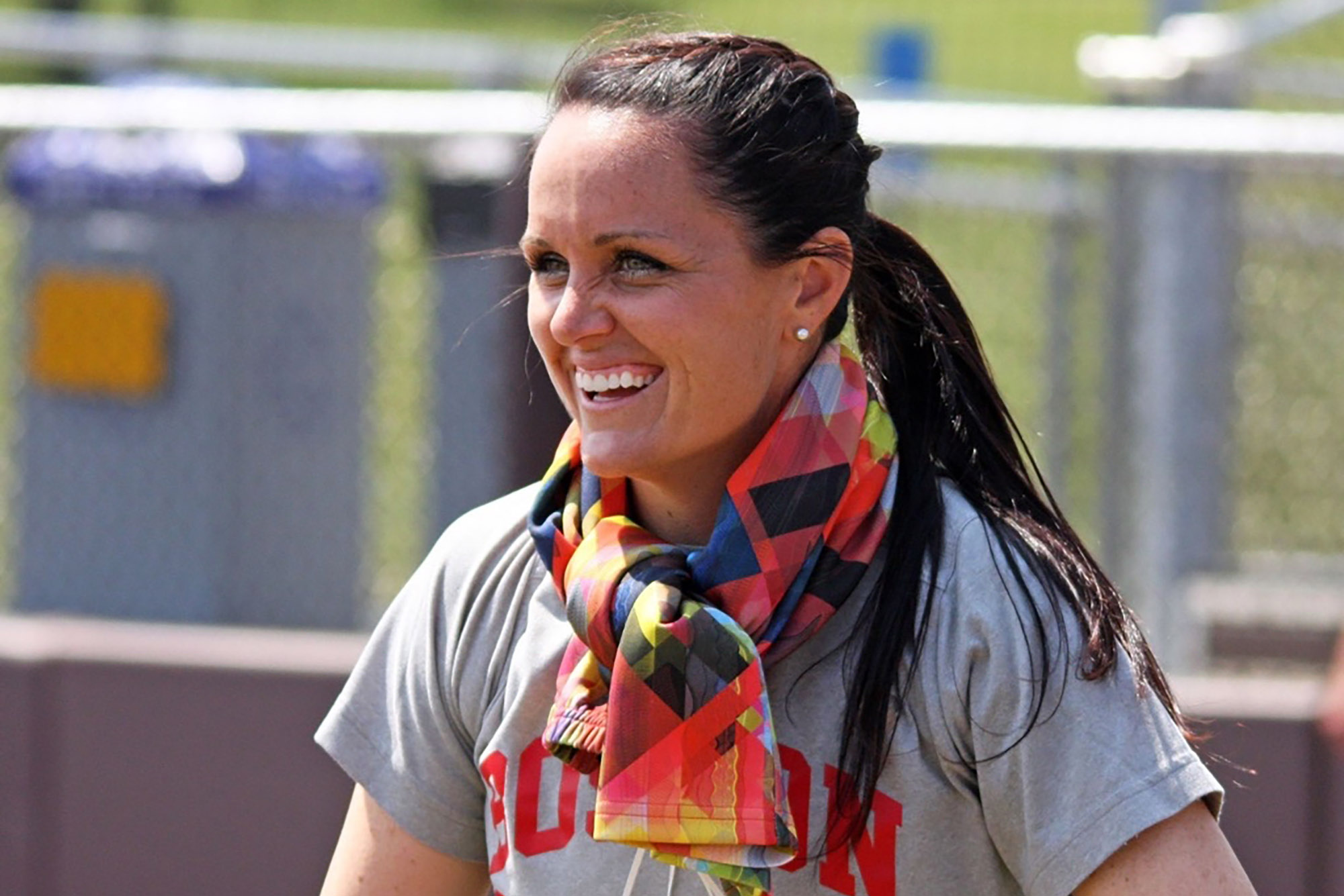 Photo: A closeup shot of Ashley Waters, a white woman with long dark hair, smiling while wearing colorful leggings around her neck.