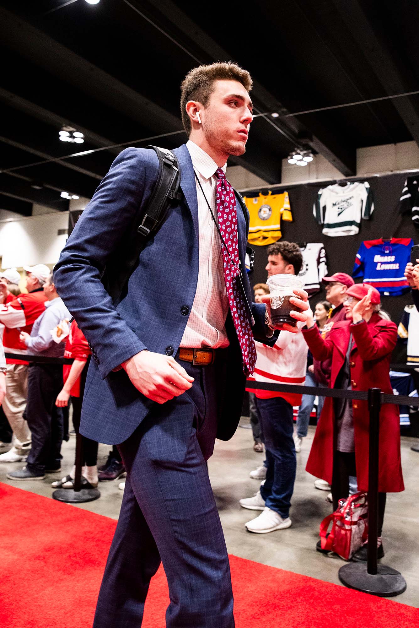 Photo: A picture of a man wearing a suit with a backpack walking down a red carpet