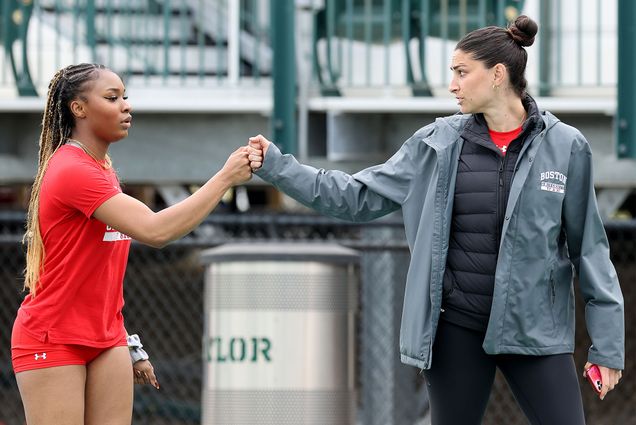 Photo: Two woman fist bumping each other at a track meet. Reigning Patriot League Indoor Women’s Field Athlete of the Meet Peace Omonzane (CAS’26) fistbumps jumps and multis coach Sara Macey.