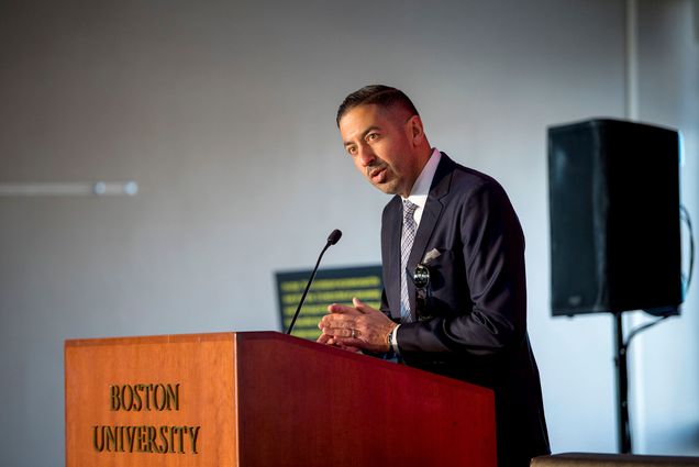 Photo: A picture of a man in a dark suit speaking at a podium. On the podium are the words "Boston University"
