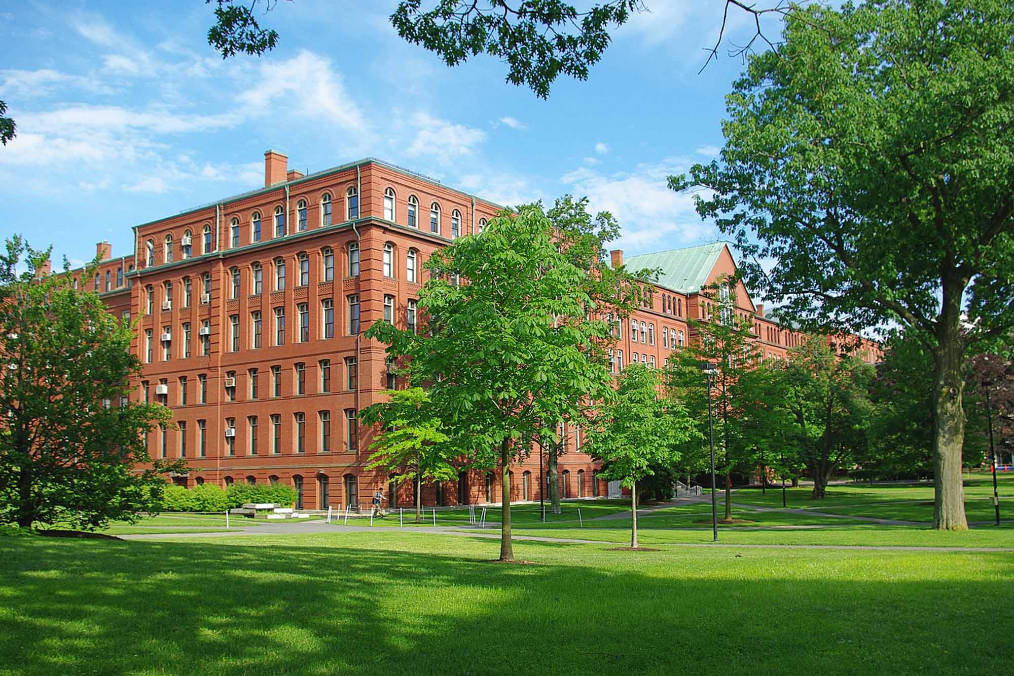 Photo: An exterior shot of the Harvard Museum of Natural History. The brick building is expansive with many windows and is surrounded by greenery