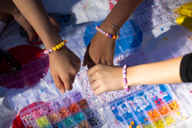 Photo: Three arms wearing colorful Pride bracelets join together in a display of friendship. The hands are of varying skin tones symbolizing diversity.