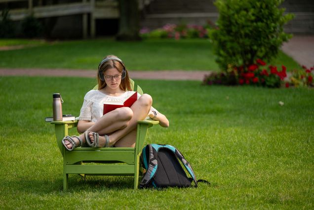 Photo: A picture of a student sitting in a lawn chair outside and reading a book