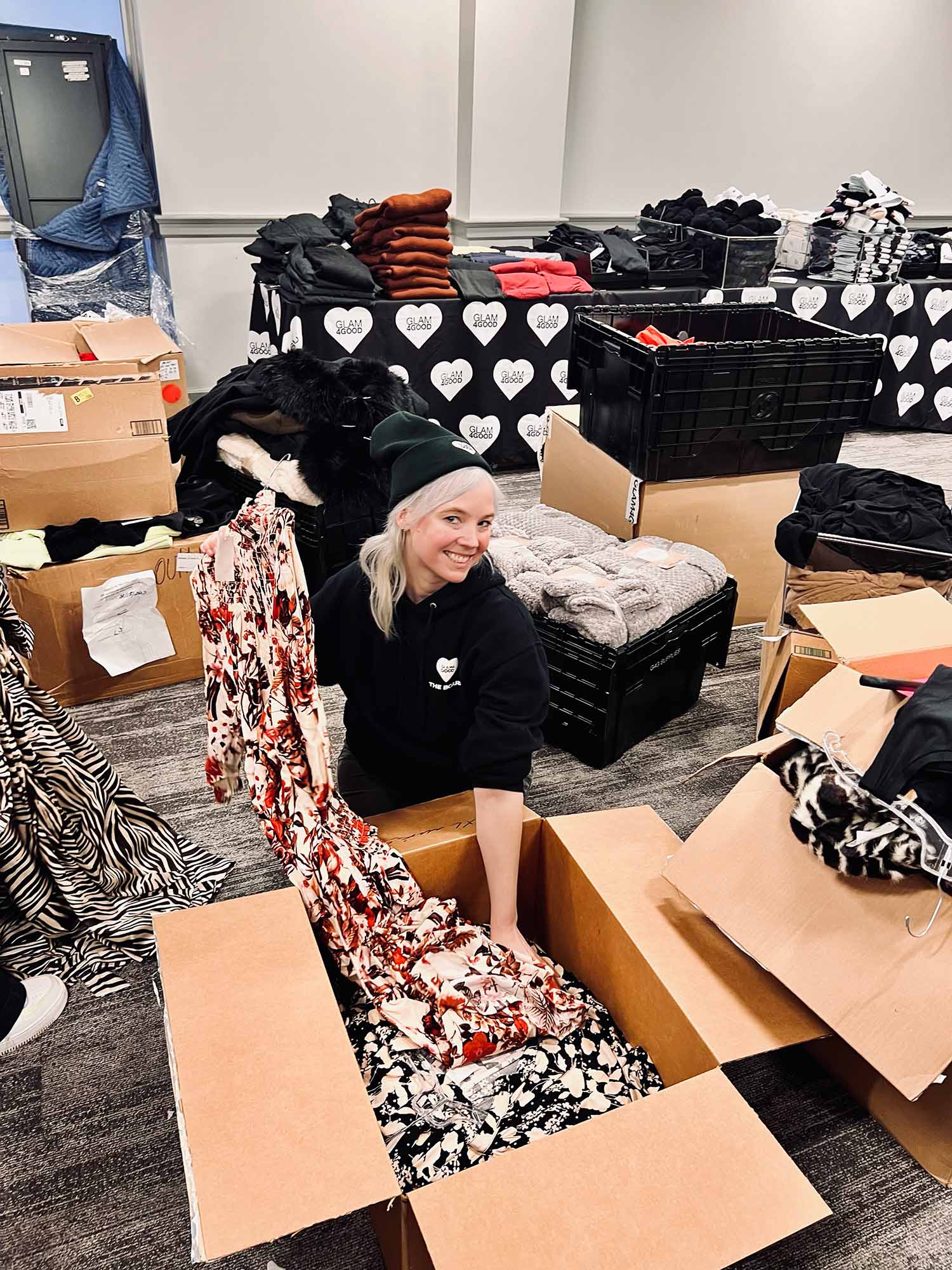 Photo: A picture of a girl with white blonde hair unpacking clothing fabric from a box