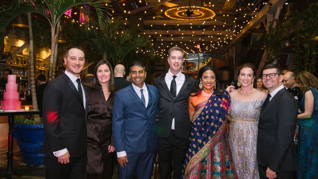 Photo: 3 men in suits embrace 3 women in formal dresses at an elegant evening event