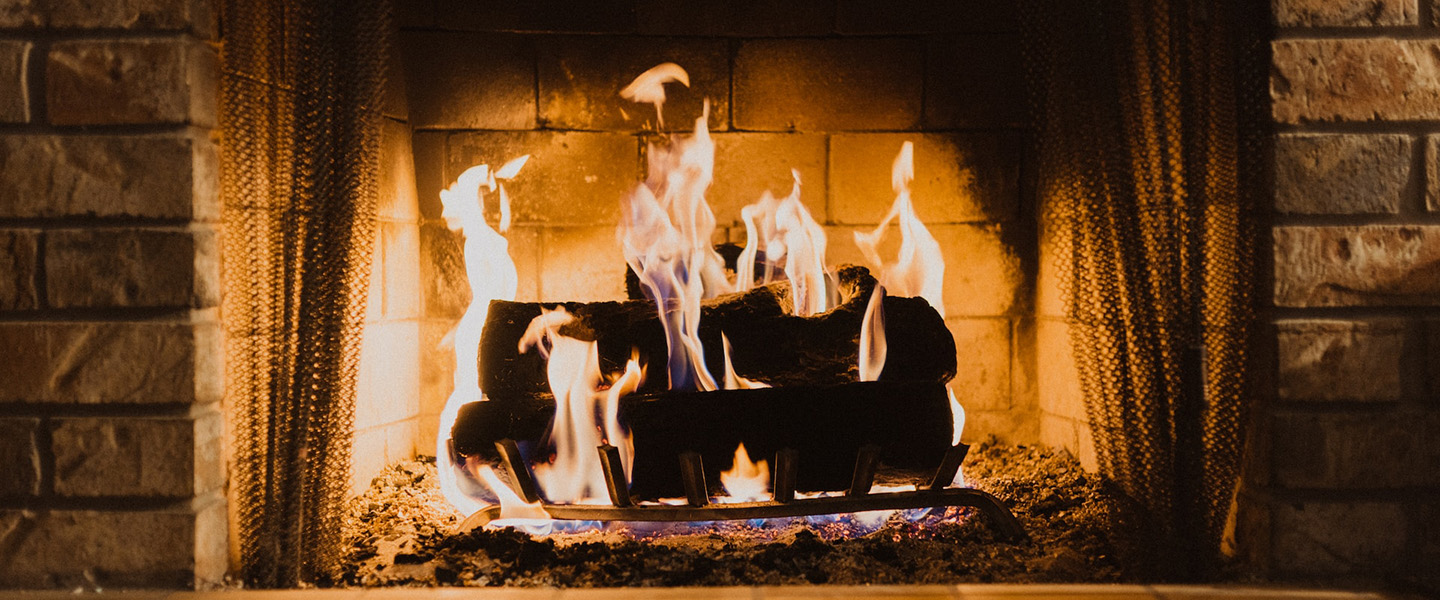 Photo: A lit fireplace is shown during the night. A few logs are shown with a blazing fire around them.