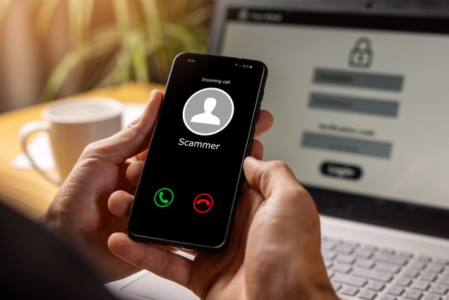 Photo: A person holding a cellphone receiving a call from someone called "Scammer"