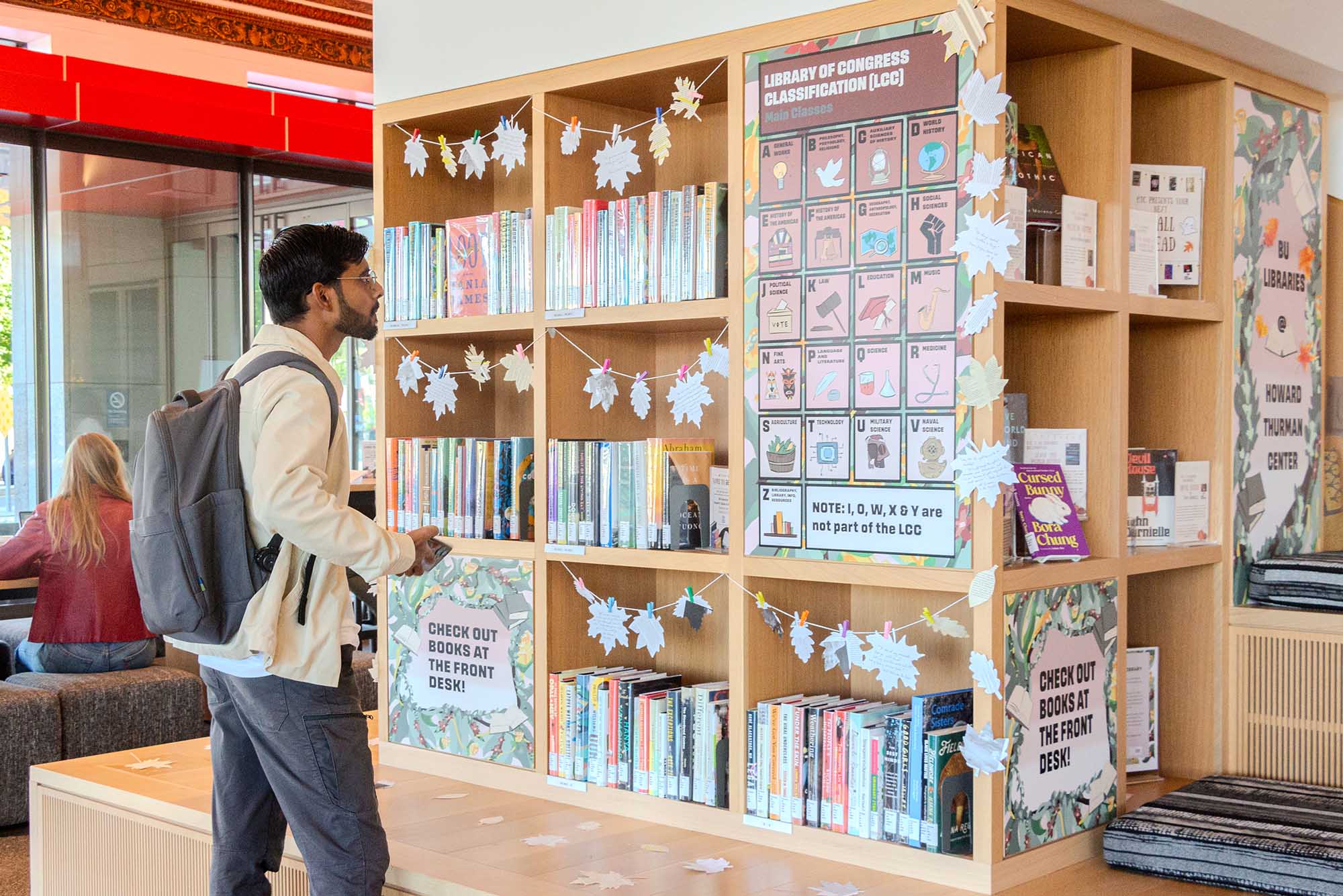 Photo: Amit Yadav, a young man with a white jacket and gray pants, checks out the Howard Thurman Center’s new Lending Library