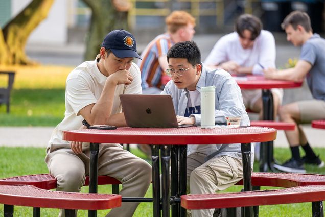 Jeremy Yu (MET’25), left, and Andy Zheng (MET’25) work together on an accounting assignment on the COM lawn Sept 13. Photo by Cydney Scott