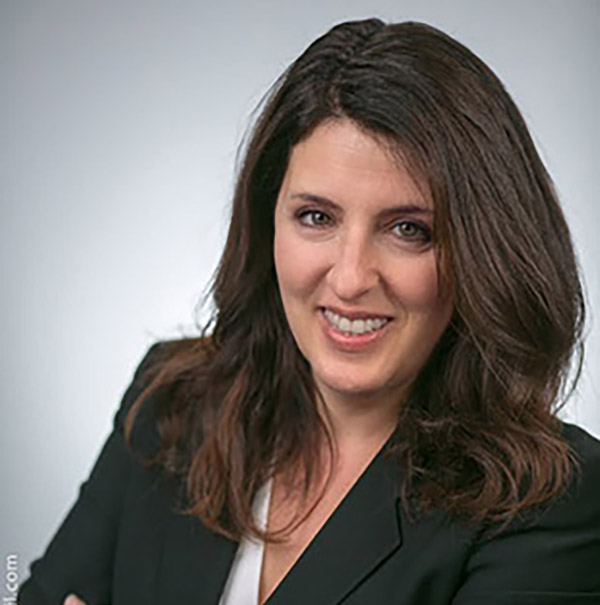 Photo: A white woman with short brown hair poses in a headshot in front of a white/gray background.
