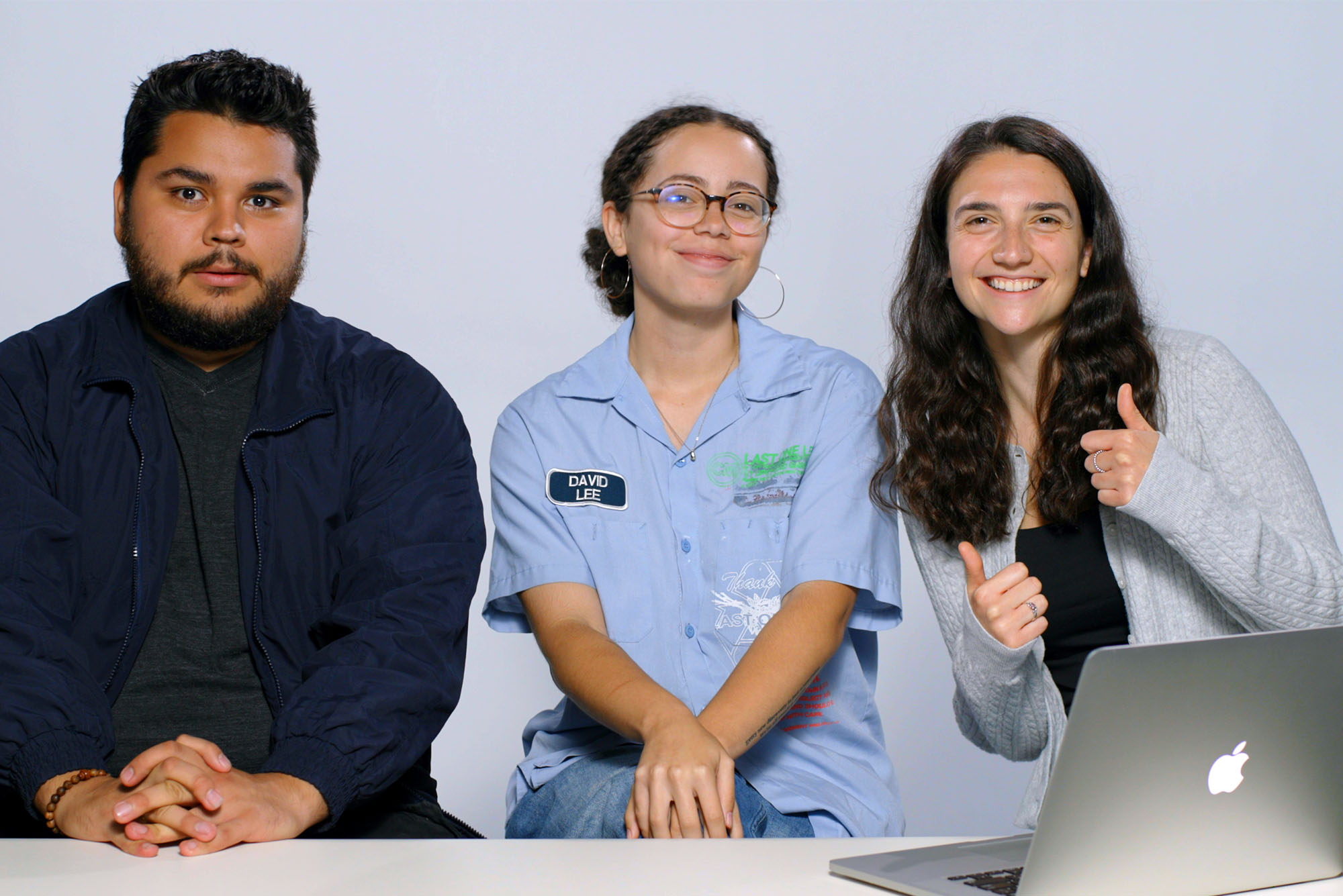 Photo: Three people sitting behind a desk with an open laptop