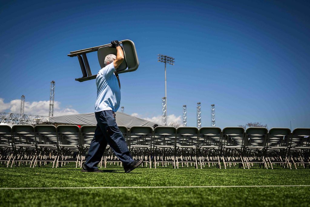 Photo: A man setting up metal foldable chairs on a field