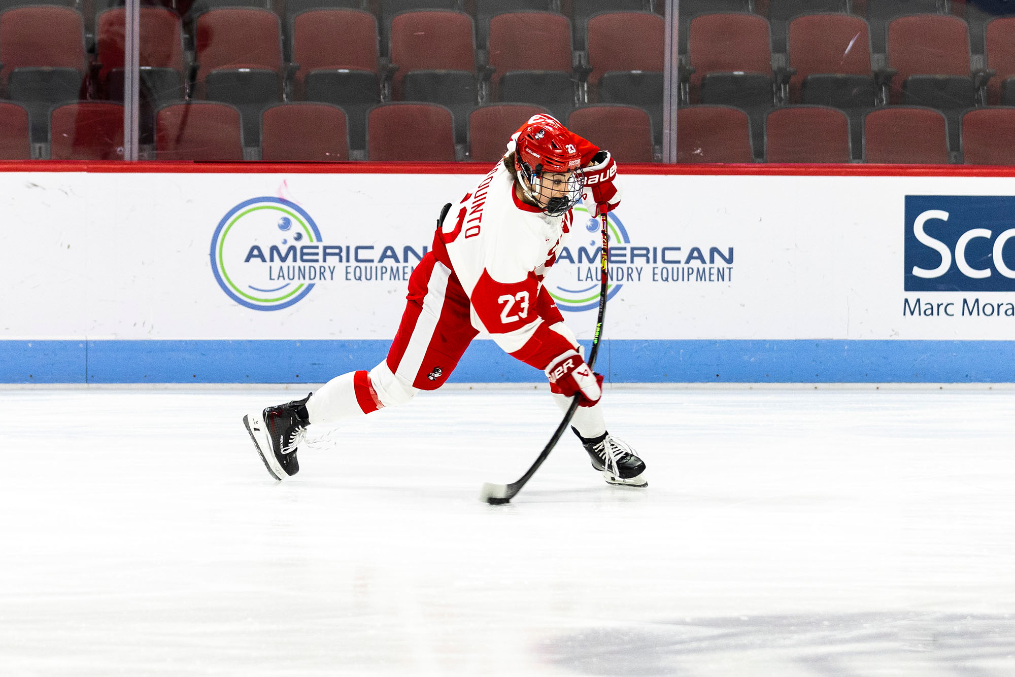Photo: A female hockey player wearing Boston University gear skating with the puck on the ice during a game