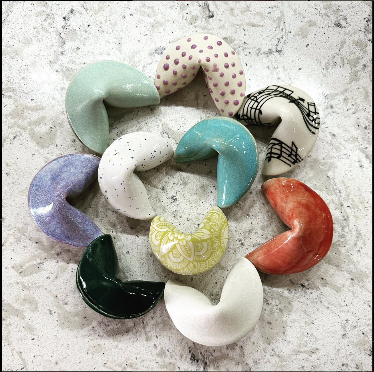Photo: Ceramic fortune cookies in a circle on a marble table.