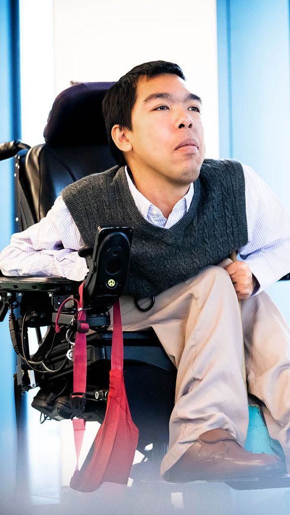 Photo: PhD student Justin Moy poses for a portrait photo in a vest and white button up