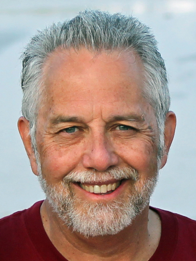 Photo: A headshot of a man with gray hair smiling