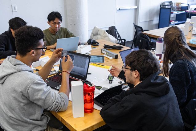 Photo: A group of young students at BU look at their computers and work on their hackathon event.