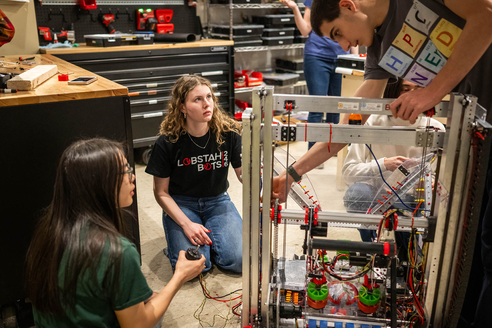 Photo: A young woman helps high school kids with their robotic project.