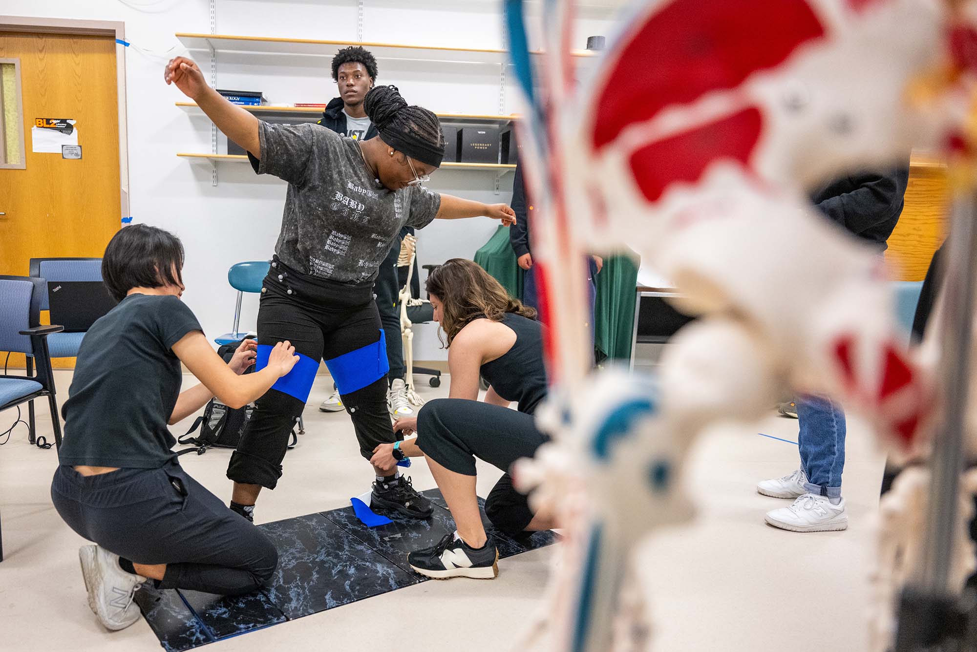 Photo: People placing sensors on a younger student during a Biomechanics Day