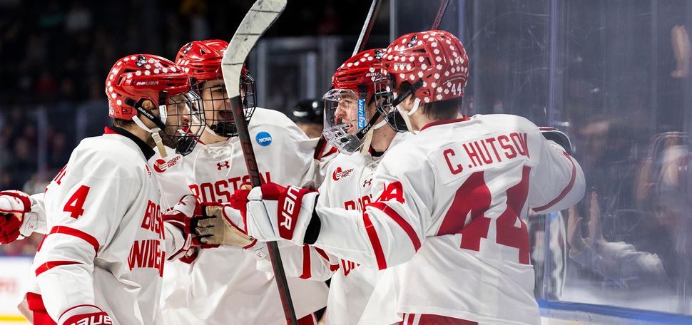 Photo: A group of BU men's hockey huddle and talk on the ice in their uniform.