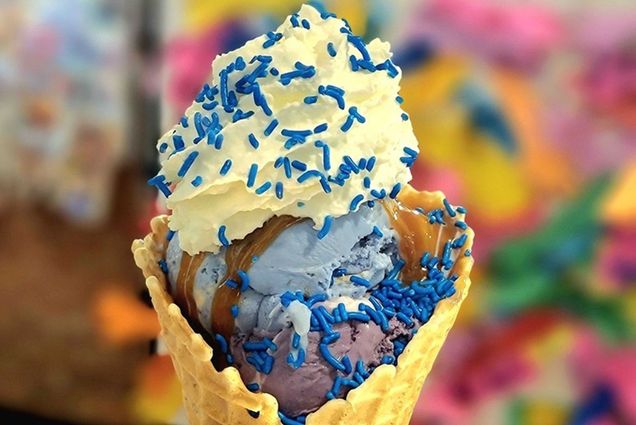 Photo: An ice cream cone with purple and blue scoops, whipped cream, and blue sprinkles on top