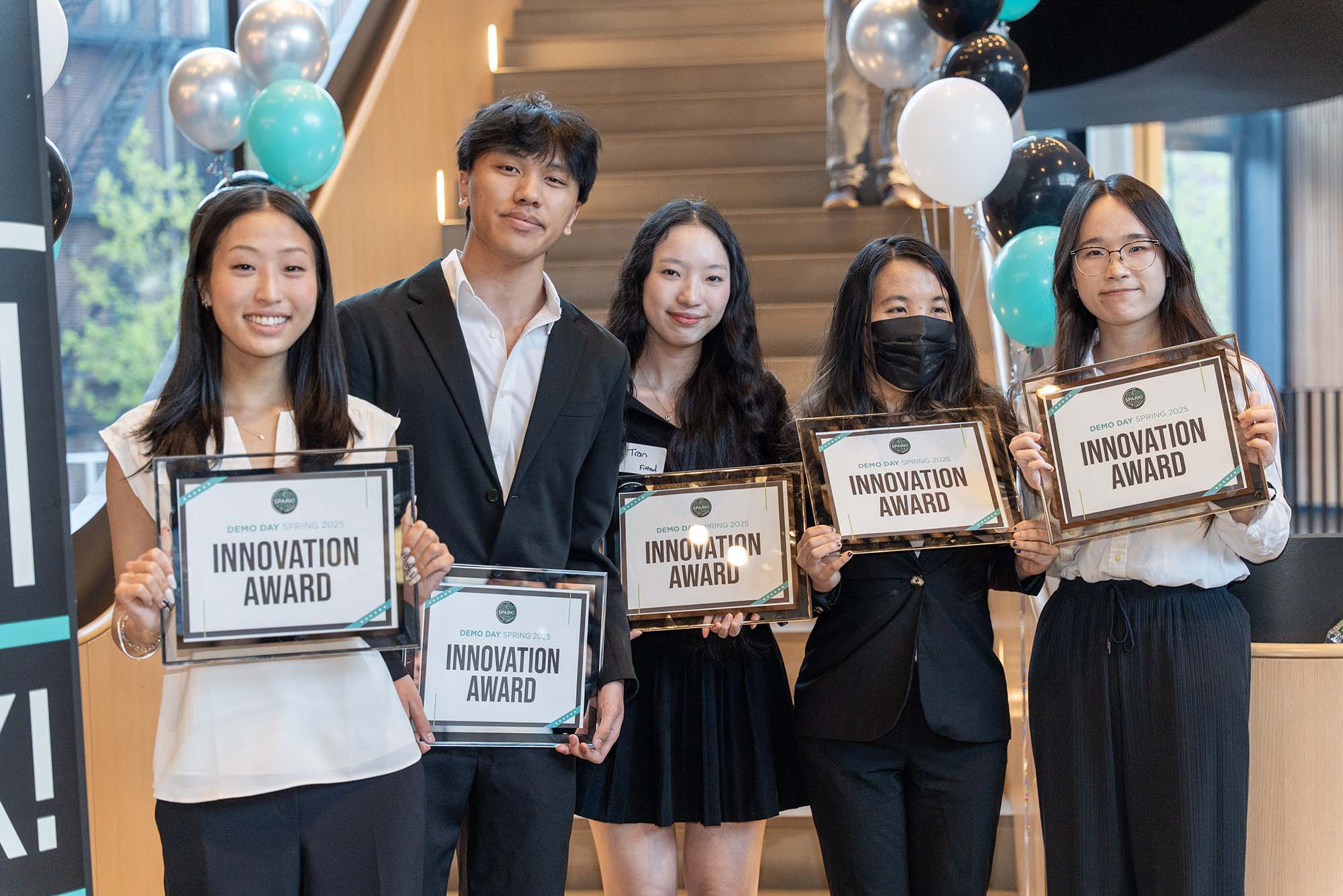 Photo: A group of students in formal attire smile for a photo, each with a certificate of their win.