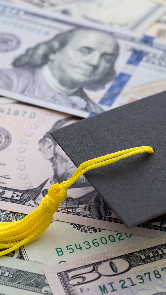 Photo: A pile of money with a graduation cap sitting on it