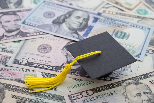 Photo: A pile of money with a graduation cap sitting on it